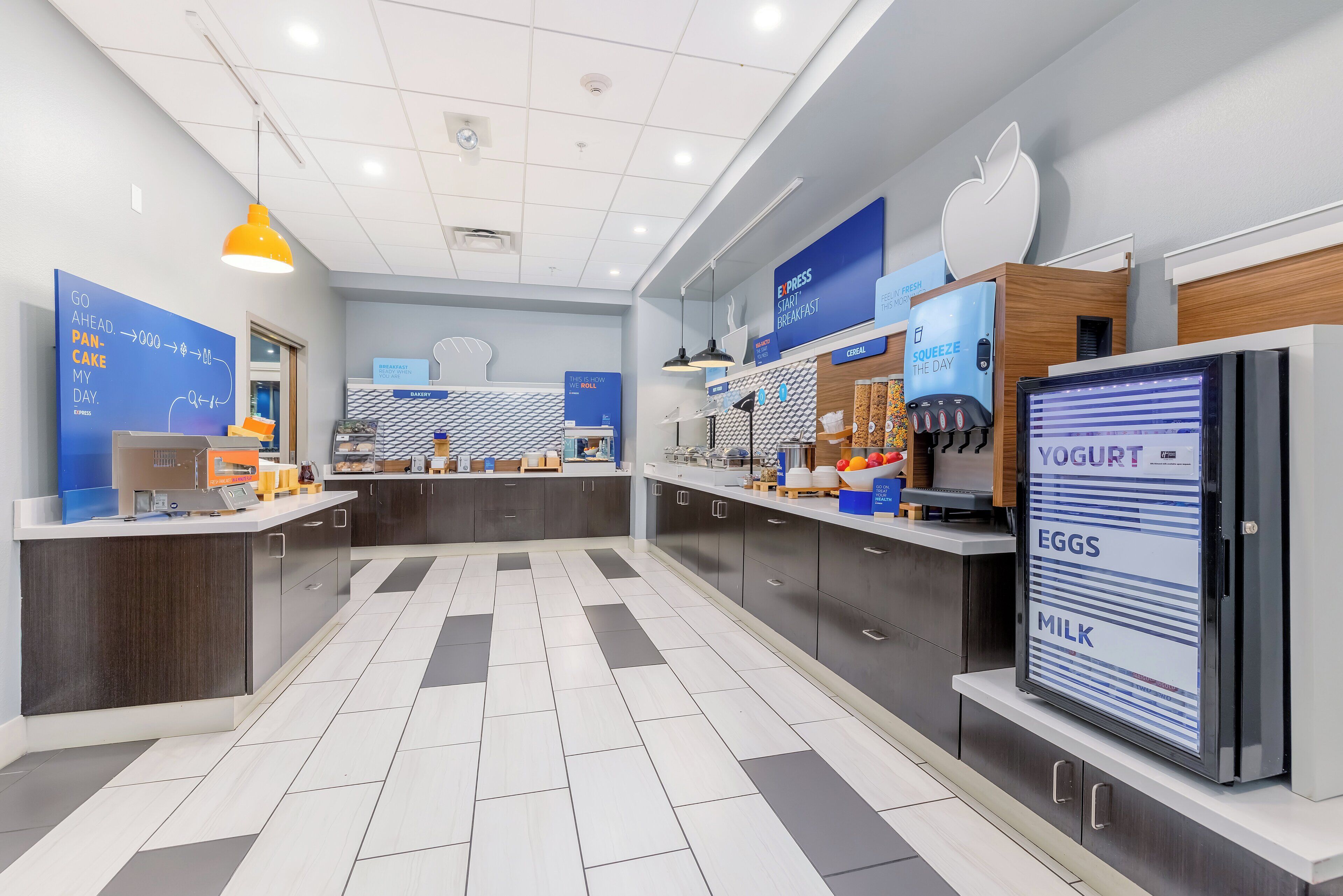 Un área de desayuno moderna con un menú digital, una máquina de café y un dispensador de yogur.