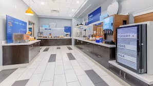 A modern breakfast area with a digital menu board, a coffee machine, and a yogurt dispenser. - Holiday Inn Express & Suites Medford by IHG (Medford)