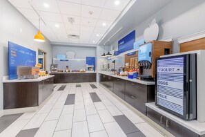A modern breakfast area with a digital menu board, a coffee machine, and a yogurt dispenser. - Holiday Inn Express & Suites Medford by IHG (Medford)