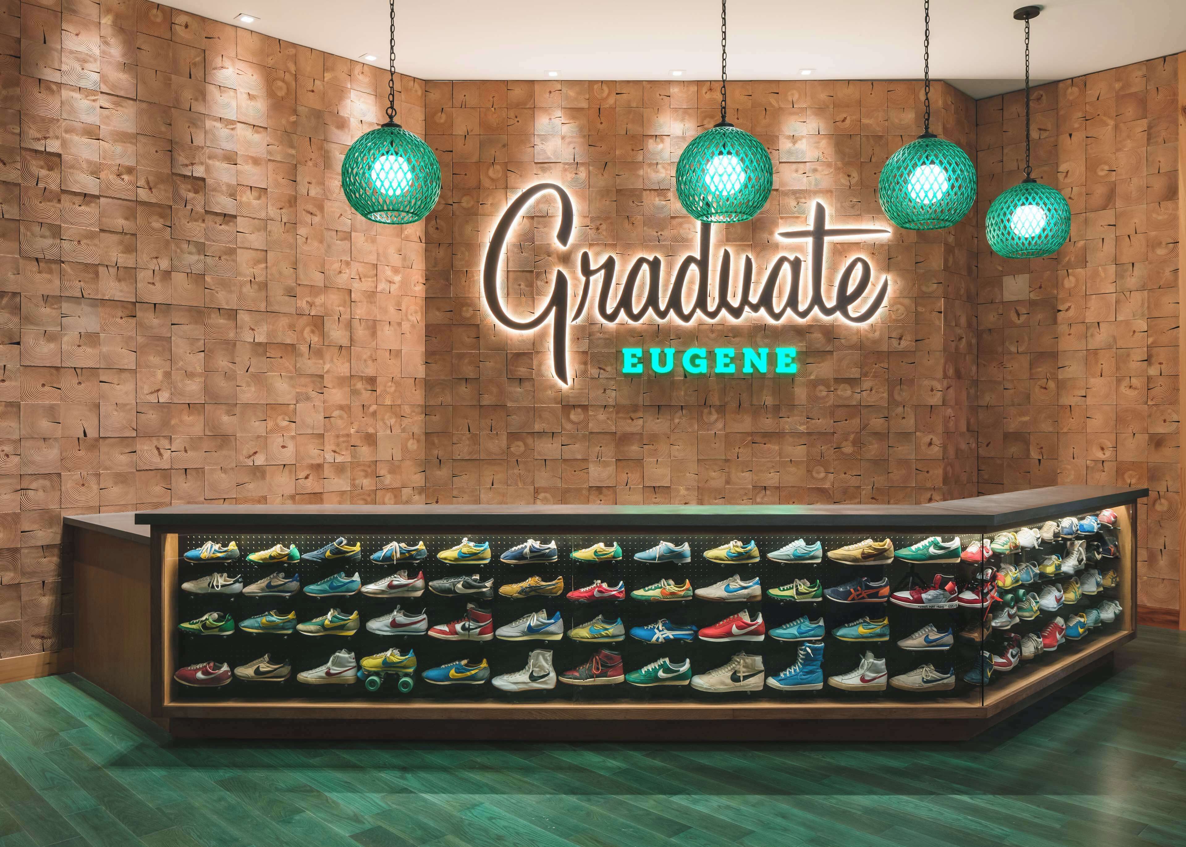 A shoe store with a wooden wall and a neon sign that reads "Graduate Eugene".