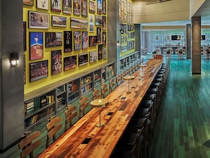 A long wooden bar with multiple stools and a wall adorned with framed sports memorabilia.