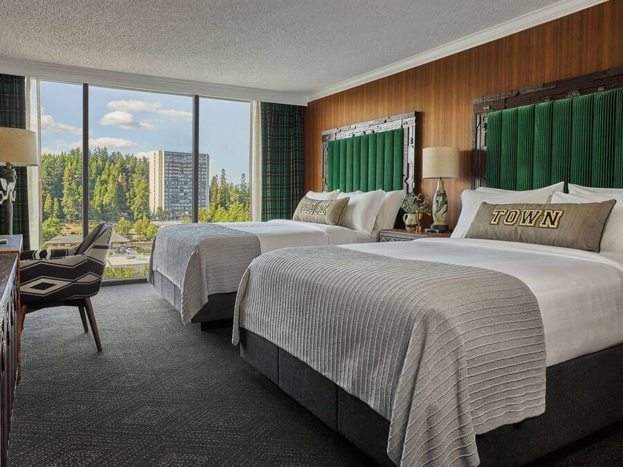 Une chambre d’hôtel avec deux lits, un bureau et une vue sur la ville.