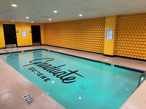 A swimming pool with a 'Graduate Eugene' sign, yellow walls, and pool rules signs.
