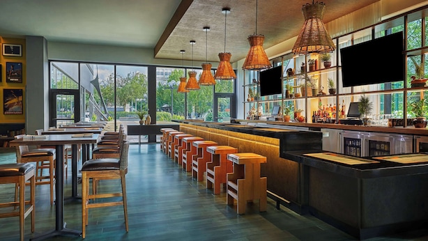 A modern bar with high stools, a long counter, and pendant lighting. - Graduate by Hilton Eugene (Eugene)