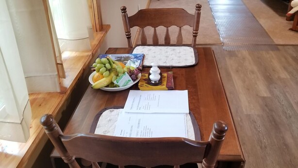 Een houten eettafel met een placemat, een fruitschaal en documenten.