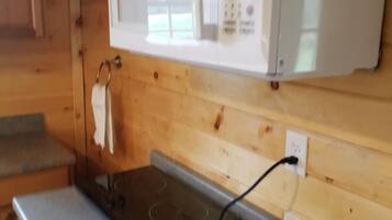 A kitchen with wooden cabinets, a microwave, a countertop, and a kettle.