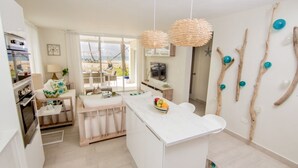 Una cocina moderna con encimera de mármol, detalles de madera y vistas al exterior.