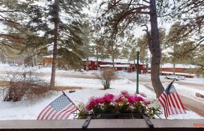 Een besneeuwde buitenruimte met een bank, Amerikaanse vlaggen en een gebouw op de achtergrond.