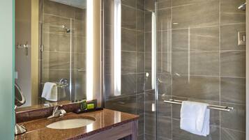 Un baño moderno con ducha envuelta en vidrio, tocador de granito y bañera.
