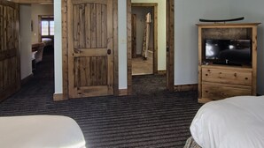 A room with a wooden door, a television on a wooden cabinet, and a bed. - Jump onto the Disciples 8 Chairlift - 7317 Creekside Condo, Ski in/Ski out (Boyne City)