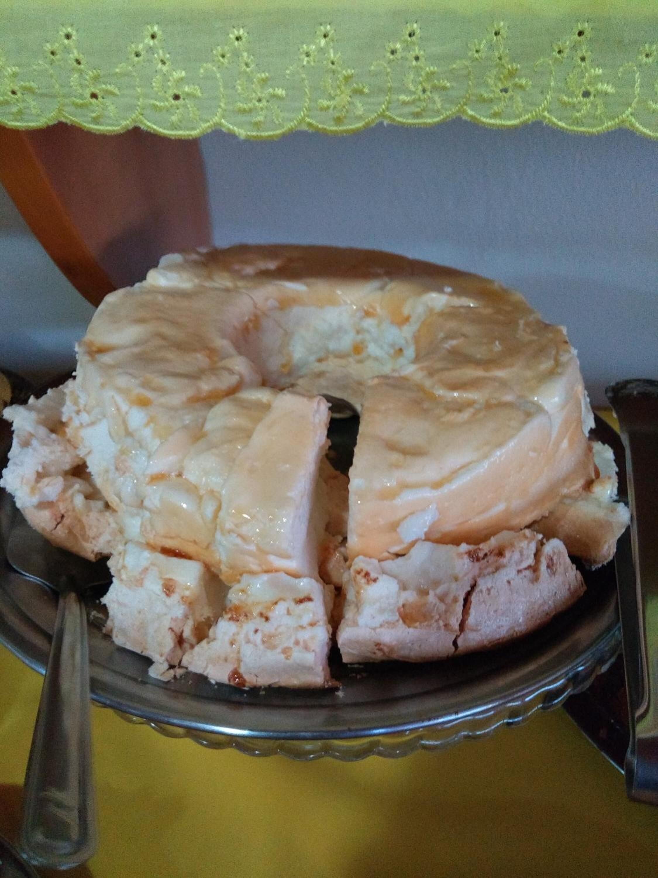 A cake with a golden-brown crust on a glass cake stand.