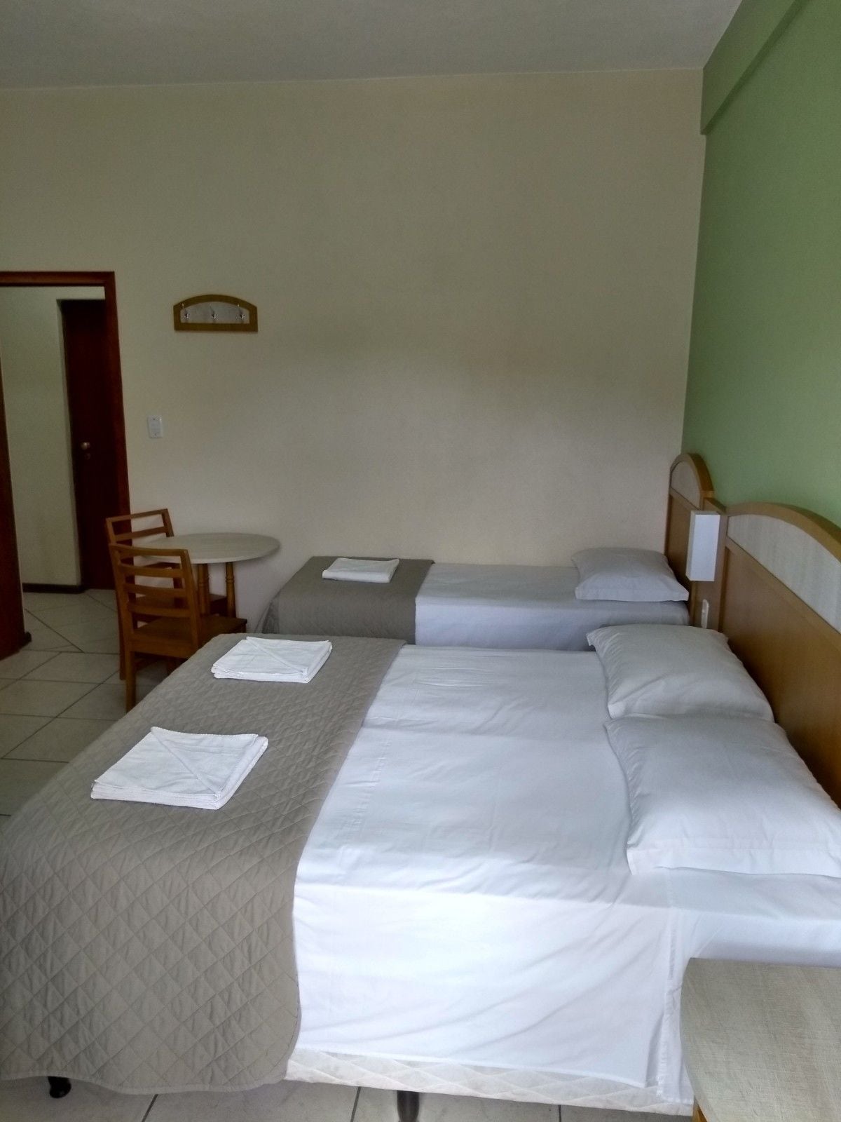 A hotel room with two beds, a small table, and a chair.
