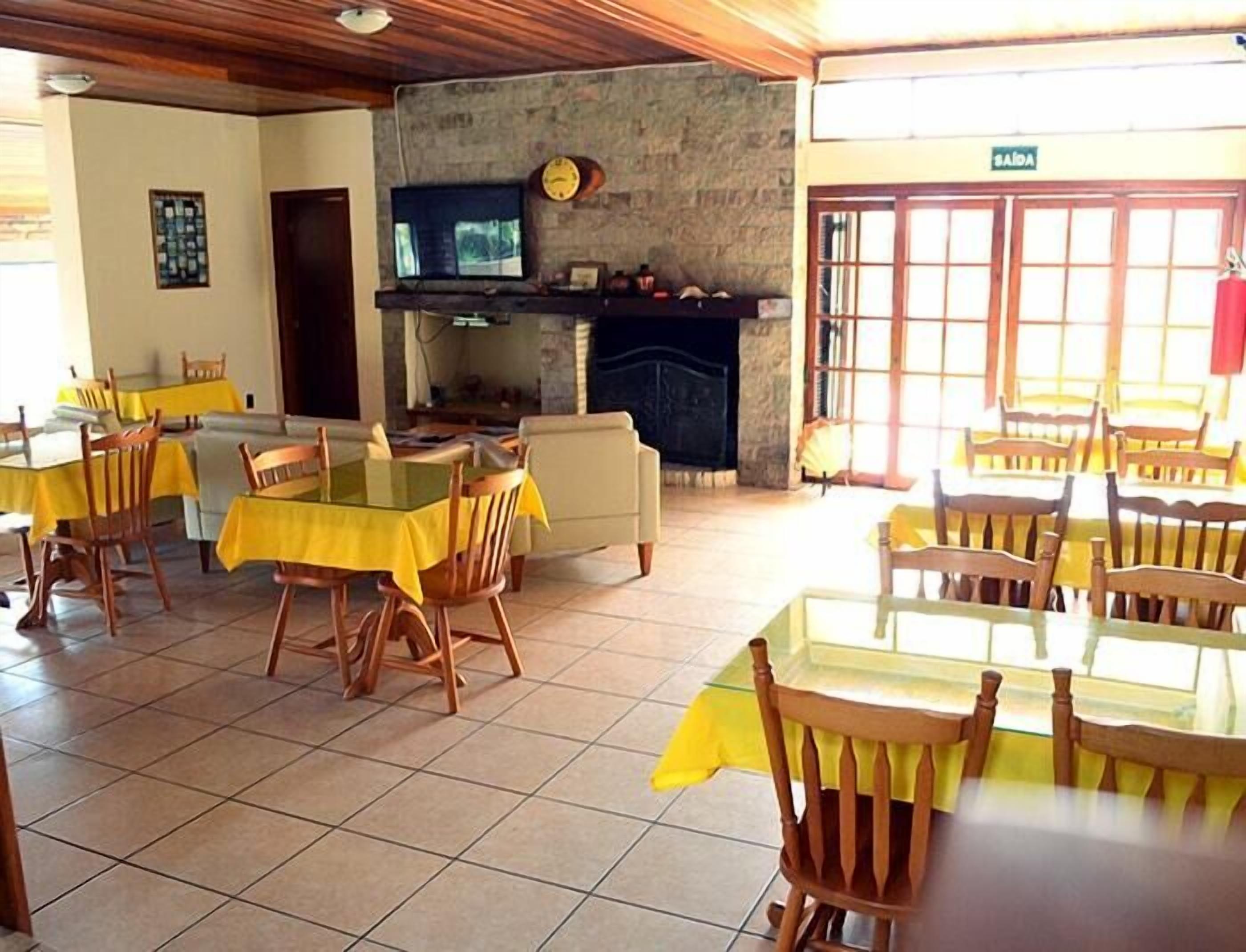 A dining area with tables and chairs, a stone wall, a fireplace, and a television.