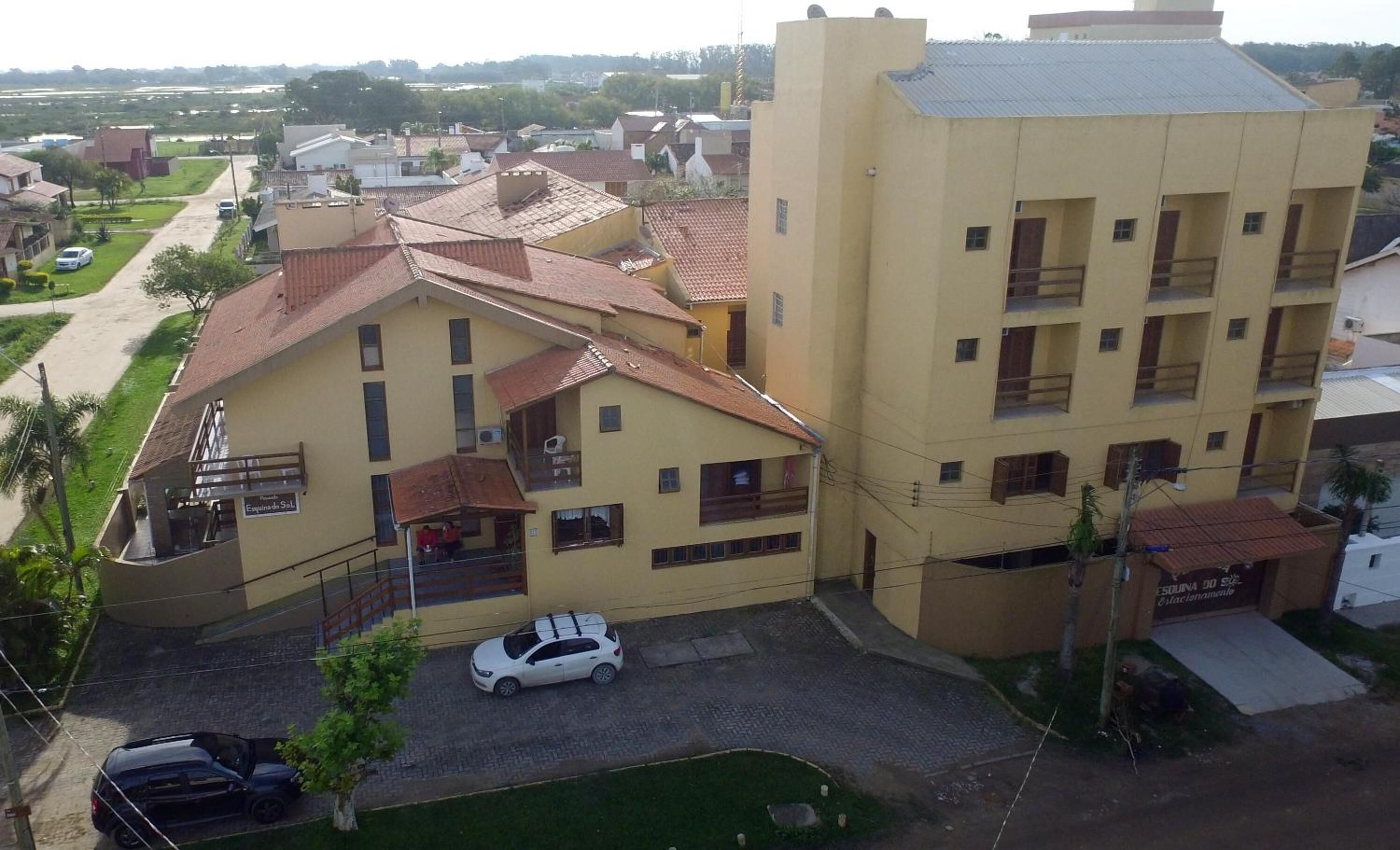 A multi-story building with a flat roof and a balcony on the ground floor.