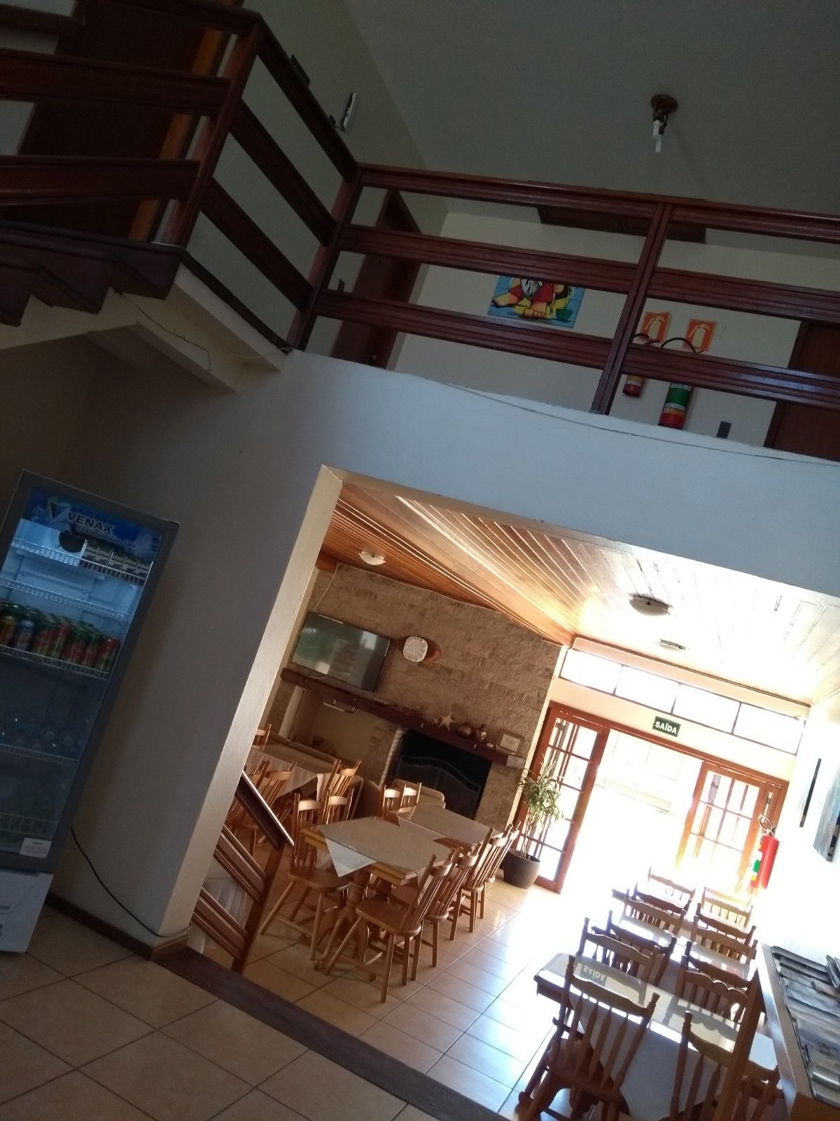 Un restaurante con techo alto, escalera de madera y vista al salón comedor.
