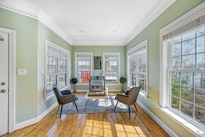 Relax in a spacious room with a high ceiling and large windows, perfect for socializing or unwinding.