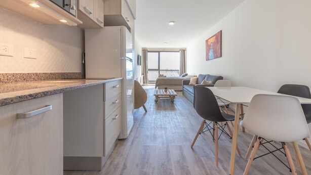 A modern kitchen with a built-in microwave, a refrigerator, and a dining area with a table and chairs. - Apt Centro Bariloche Cochera Incluida II (San Carlos de Bariloche)