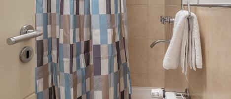 A bathroom with a shower curtain, a bathtub, and a toilet.