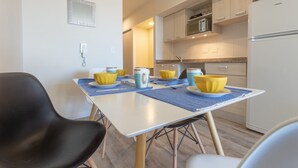 A modern kitchen with a dining table set for four, featuring yellow and blue tableware. - Apt Centro Bariloche Cochera Incluida II (San Carlos de Bariloche)