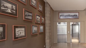 A hallway with framed black and white photographs on the walls, a stone pillar, and two elevators. - Apt Centro Bariloche Cochera Incluida II (San Carlos de Bariloche)