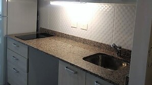 A compact kitchen with a granite countertop, stainless steel sink, and integrated microwave. - Apt Centro Bariloche Cochera Incluida II (San Carlos de Bariloche)