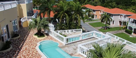 Un complex turístic amb piscina, palmeres i vista a l'oceà.