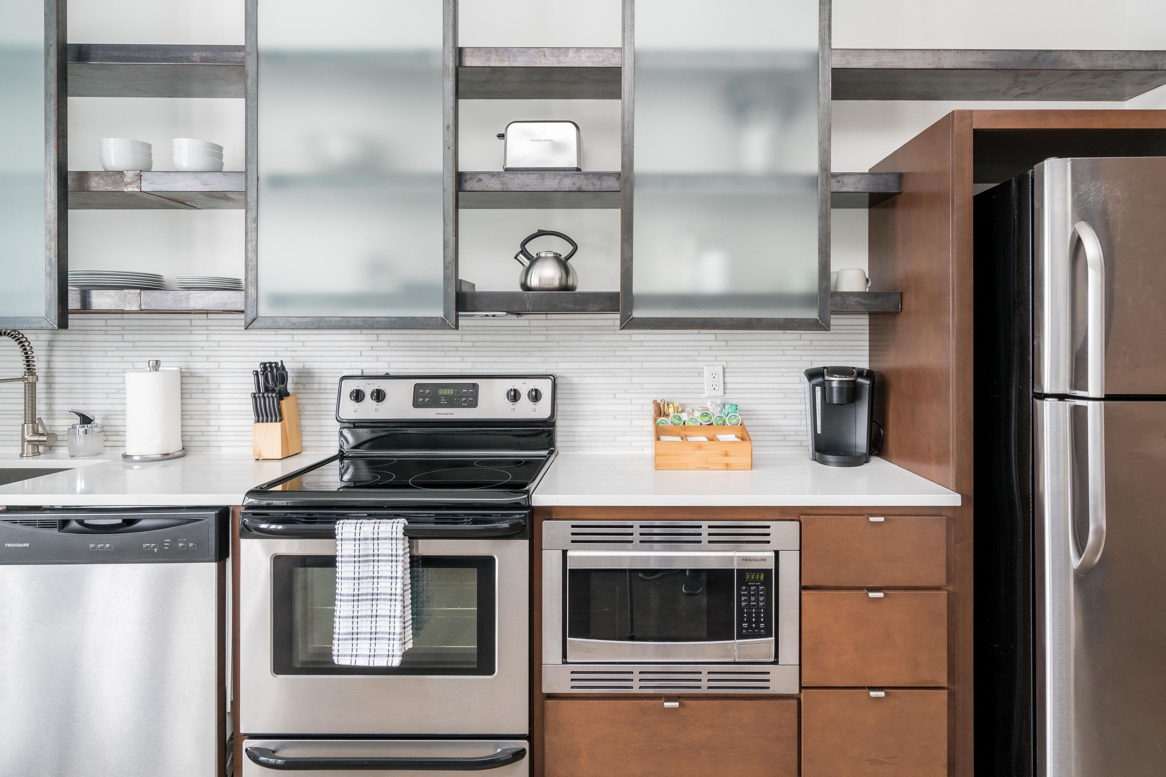 A modern kitchen with stainless steel appliances, wooden cabinets, and a built-in microwave.