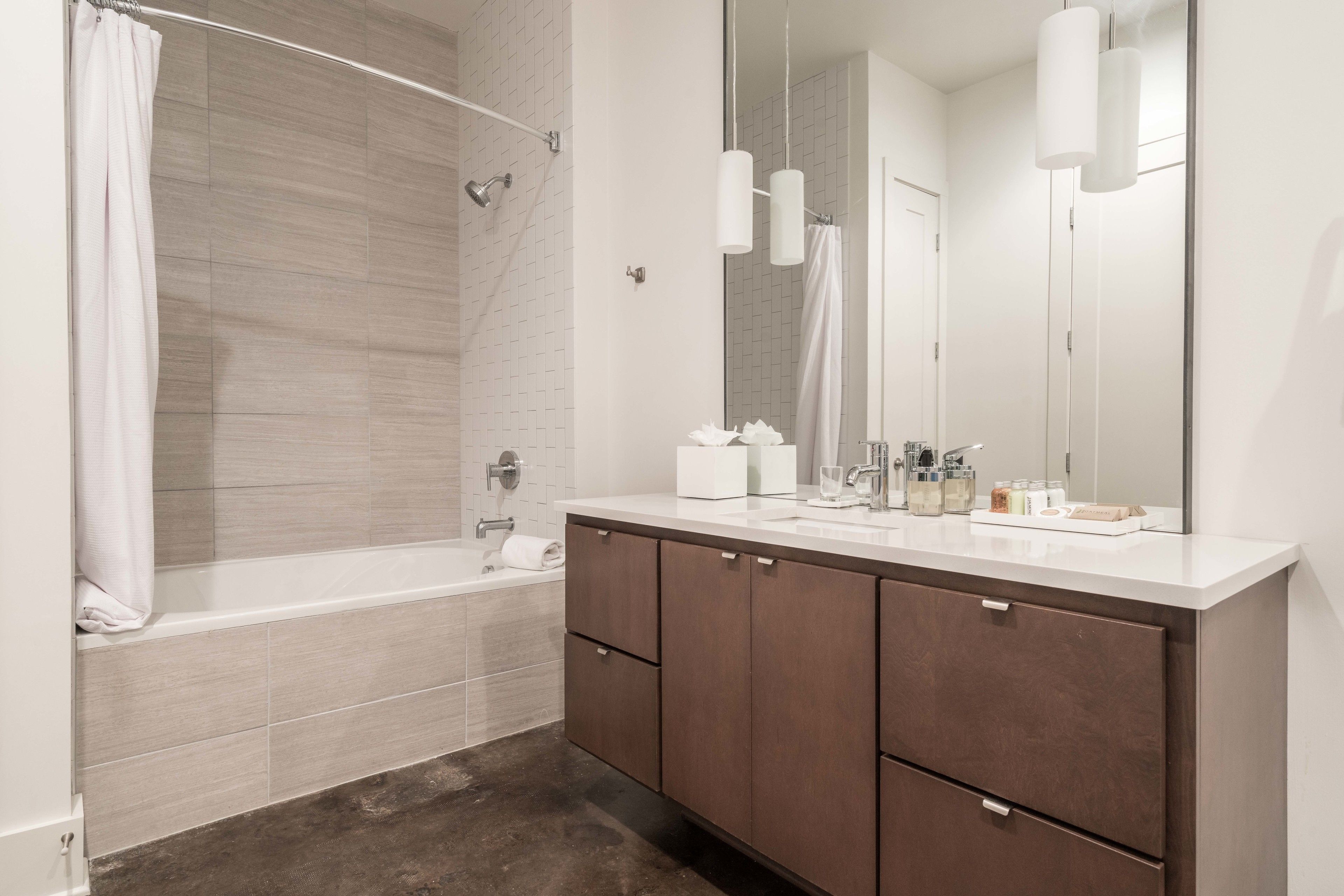 A modern bathroom with a bathtub, a large mirror, and a vanity with cabinets.