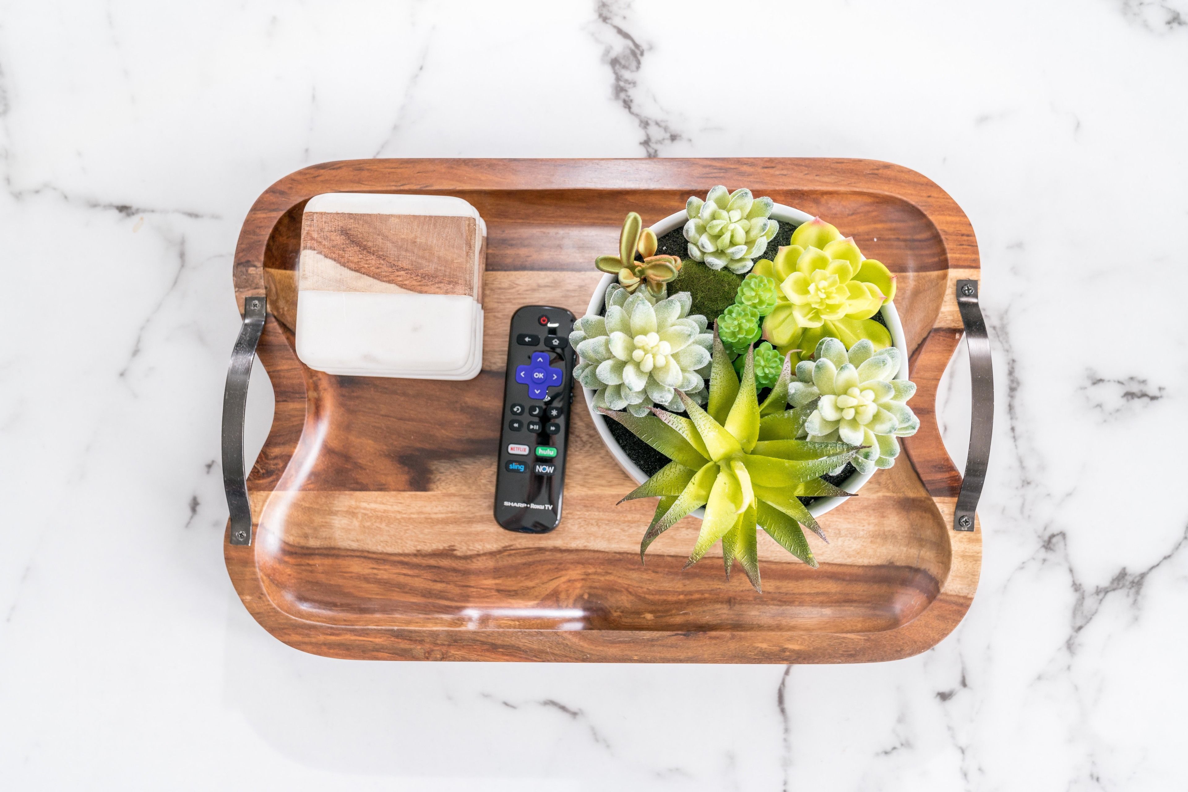 Un plateau en bois avec une télécommande, un savon et une petite plante succulente en pot.