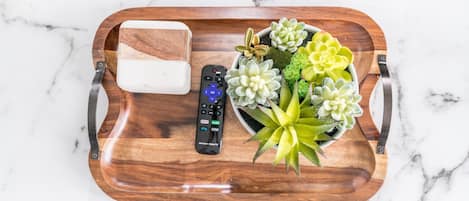 Un plateau en bois avec une télécommande, un savon et une petite plante succulente en pot.