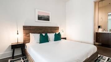 Ein Schlafzimmer mit einem hölzernen Kopfteil, weißer Bettwäsche und einem geometrischen Teppich.
