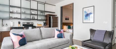 A modern living room with a grey sofa, a coffee table with a magazine, and a black leather chair.