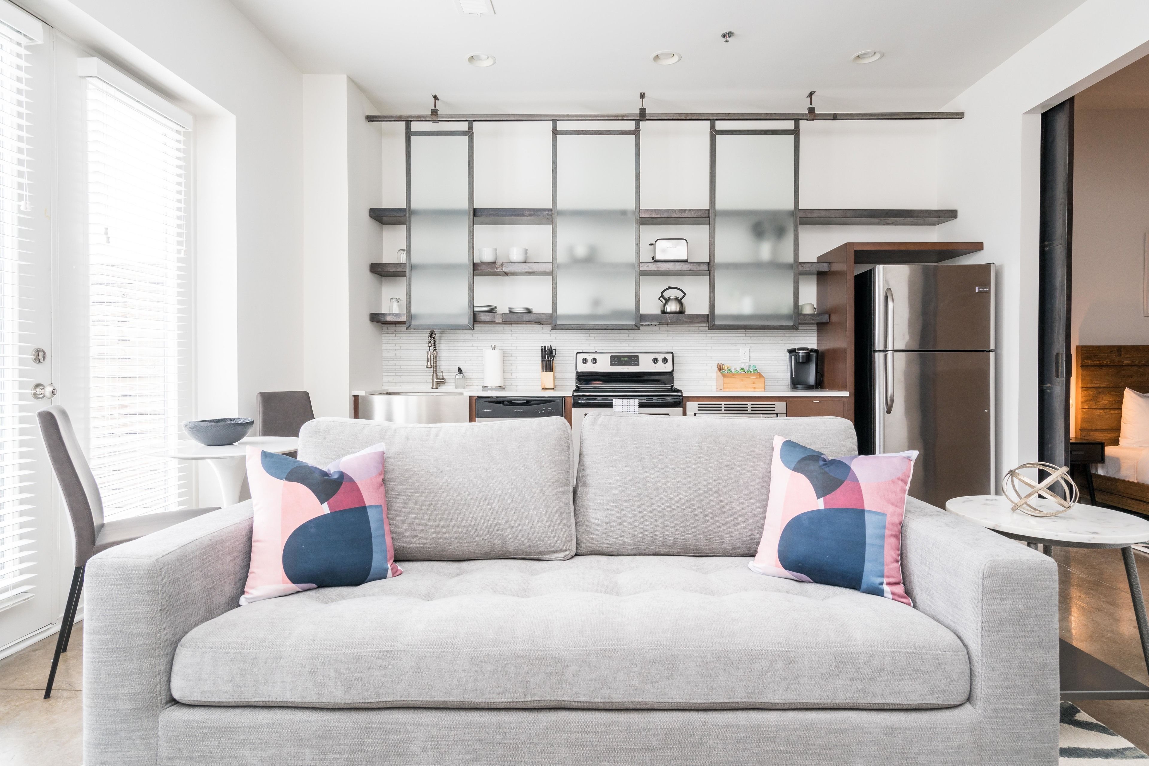 Eine moderne Küche mit grauem Sofa, einem Esstisch und einer Kücheninsel.