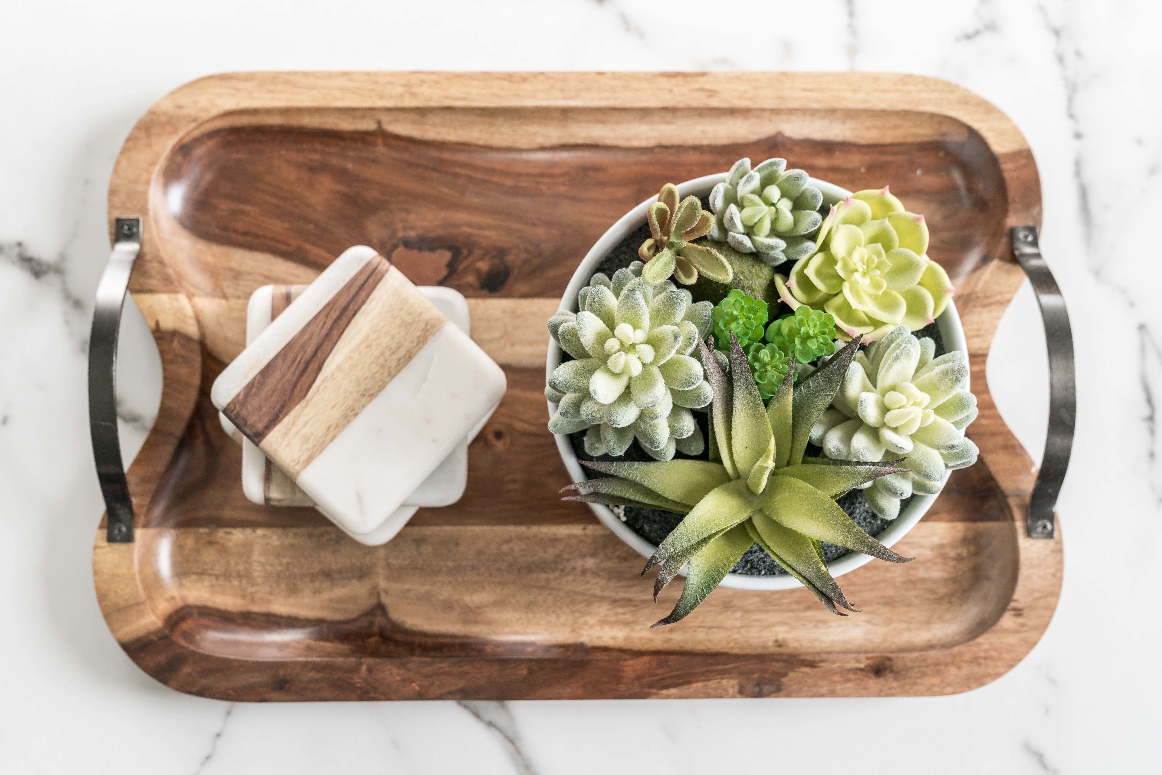 A wooden tray with a small white container and a potted succulent plant.