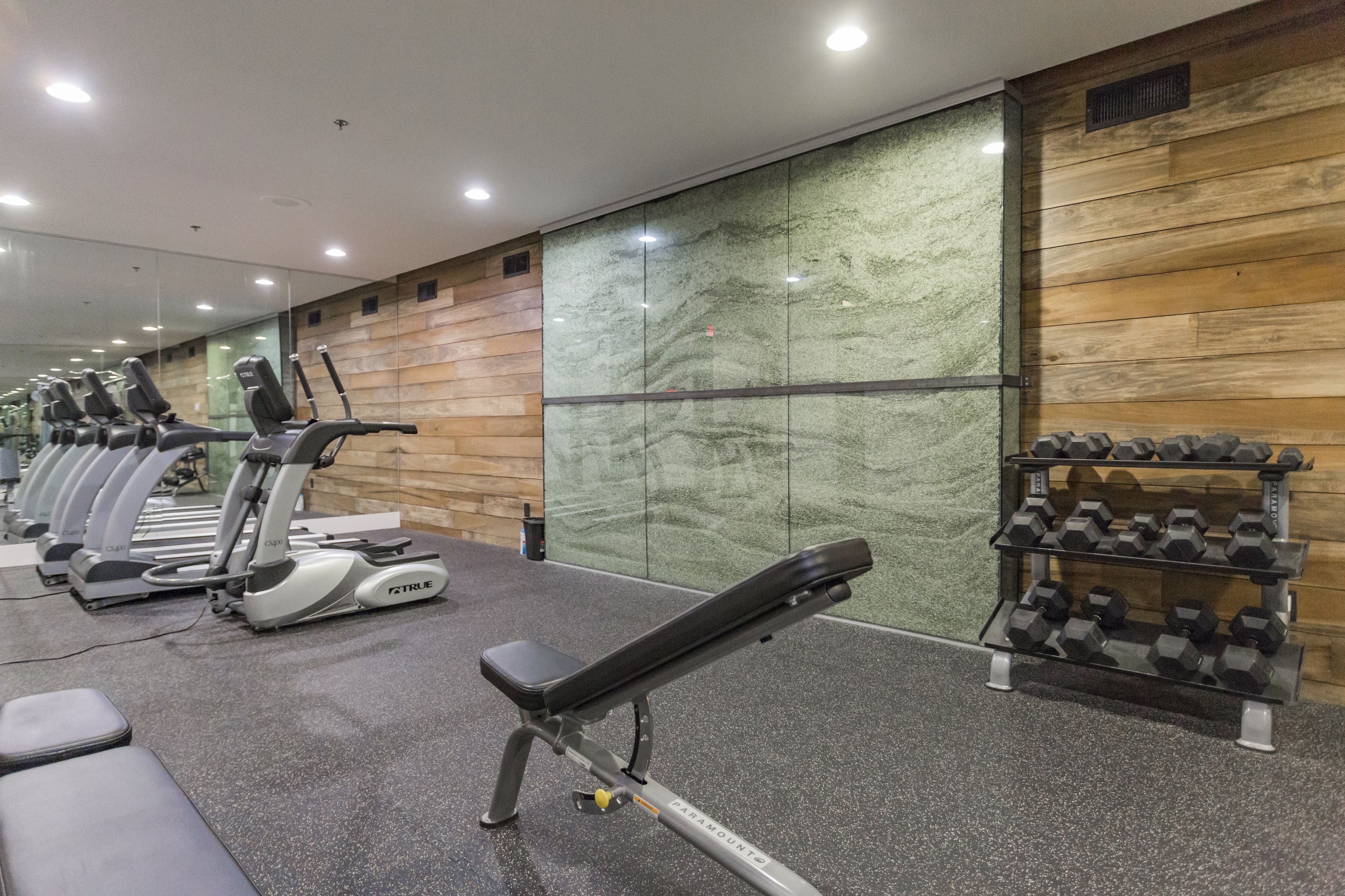 Un gimnasio con equipo de ejercicio, bancos y mancuernas.