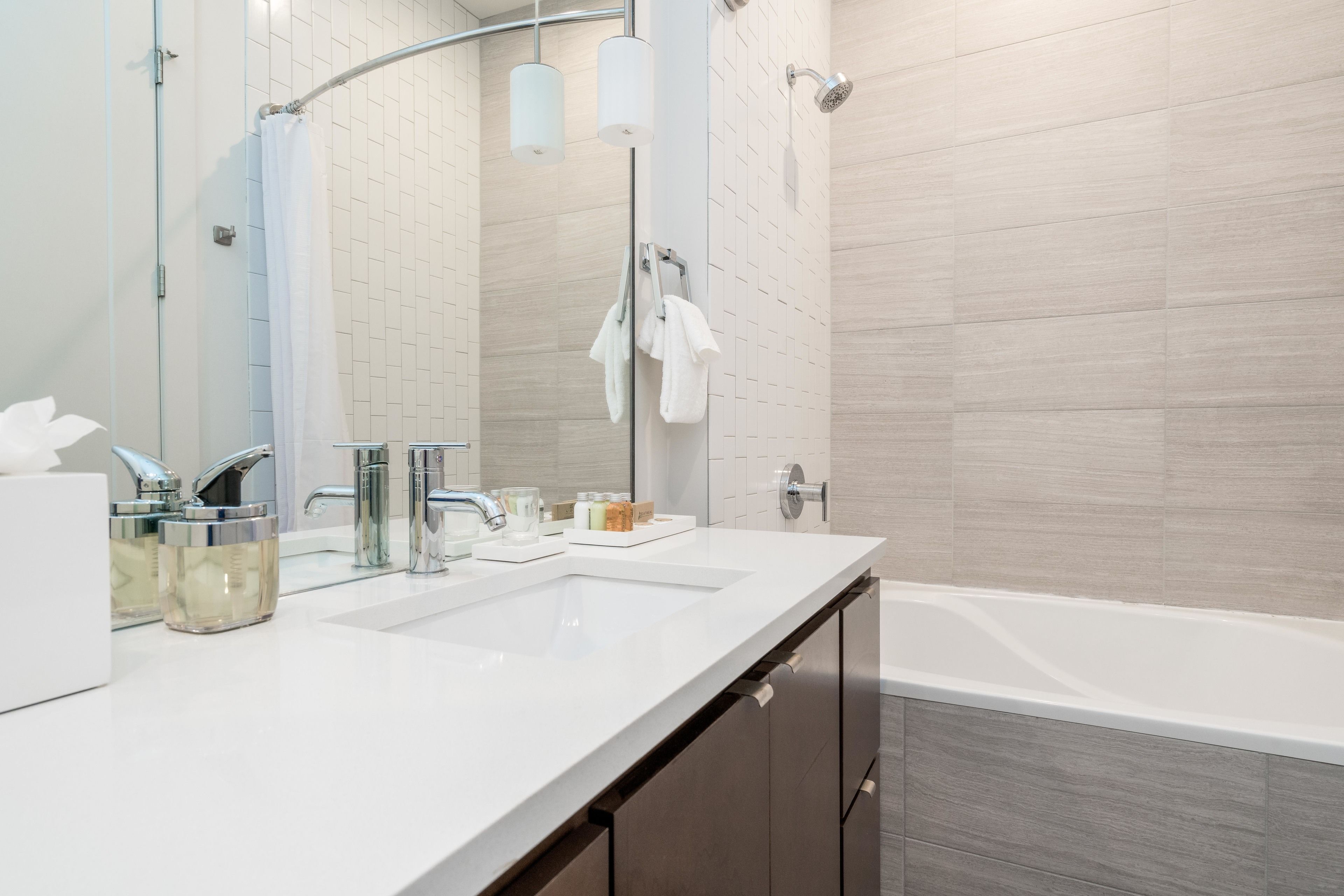 Un baño moderno con un lavabo blanco, dos espejos, una ducha con puerta de cristal y una bañera.