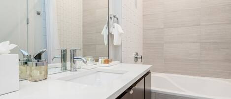 Un baño moderno con un lavabo blanco, dos espejos, una ducha con puerta de cristal y una bañera.