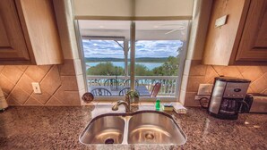 A kitchen with a double sink, a coffee maker, and a view of a lake through a window. - Endless Tranquility Cl1105h 3 Bedroom Home by RedAwning (Canyon Lake)