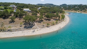 A coastal area with a sandy beach, a clear turquoise sea, and scattered trees. - Endless Tranquility Cl1105h 3 Bedroom Home by RedAwning (Canyon Lake)