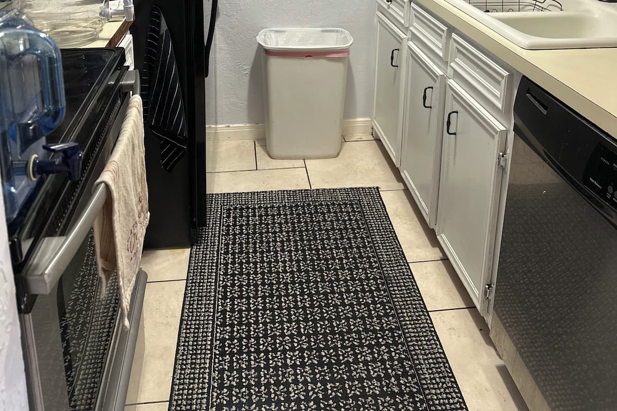 Een compacte keuken met een koelkast, koffiezetapparaat, prullenbak en een spoelbak.