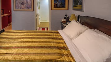 Habitación de hotel con una cama grande, una mesita de noche con lámpara y dos cuadros en la pared.