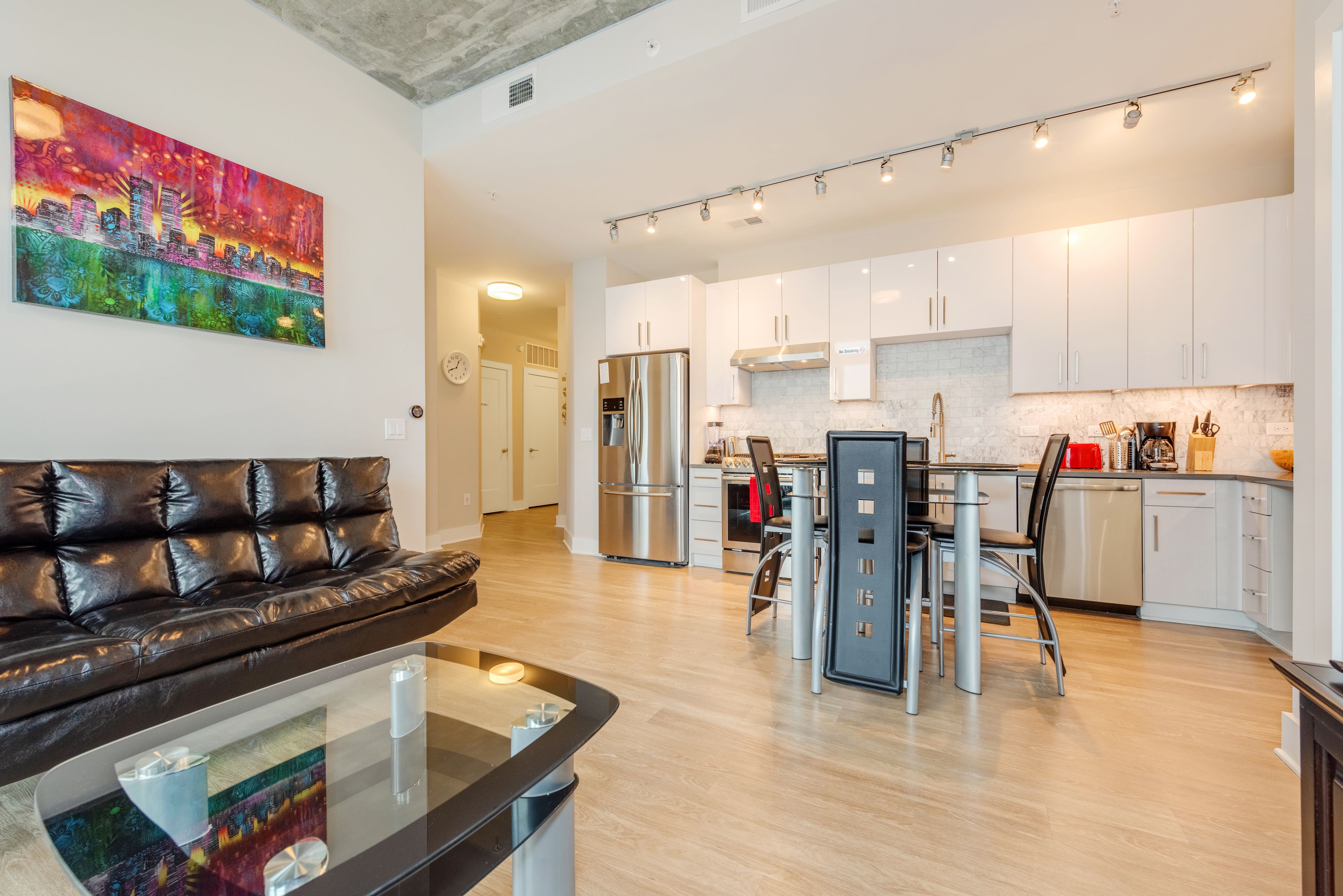 A modern kitchen with white cabinets, stainless steel appliances, and a dining area with a glass table and chairs.