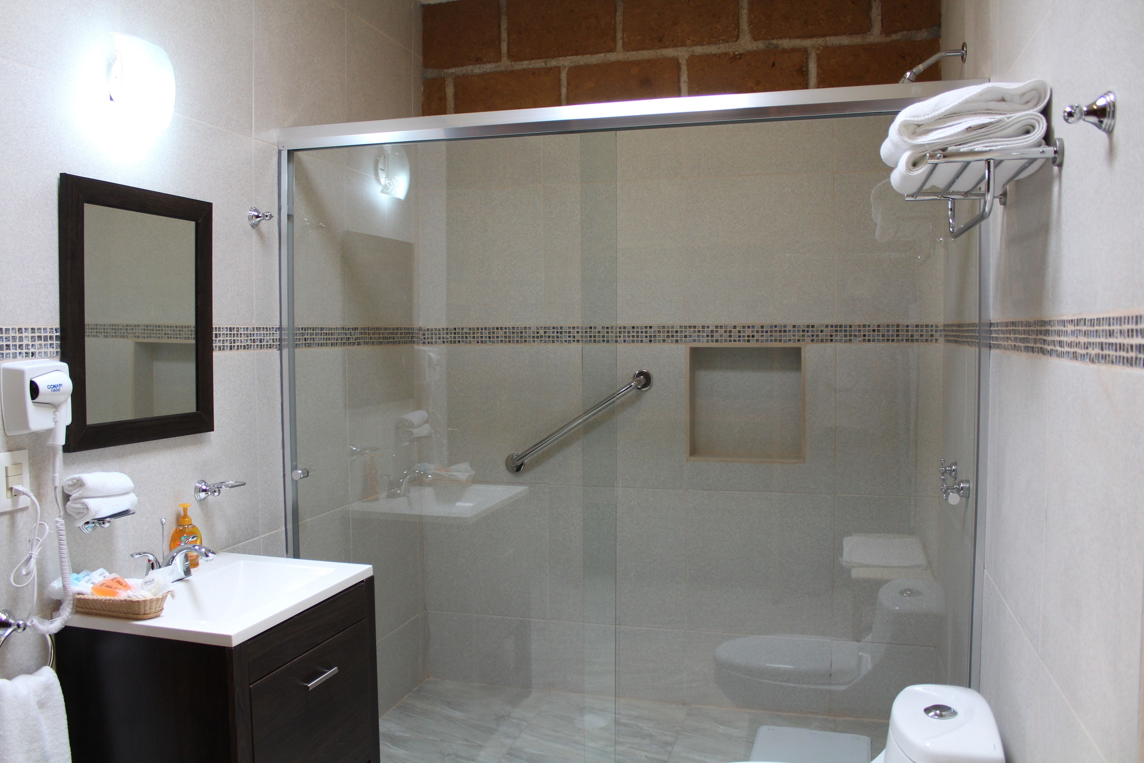 A modern bathroom with a glass-enclosed shower, a white sink, a mirror, and a towel rack.