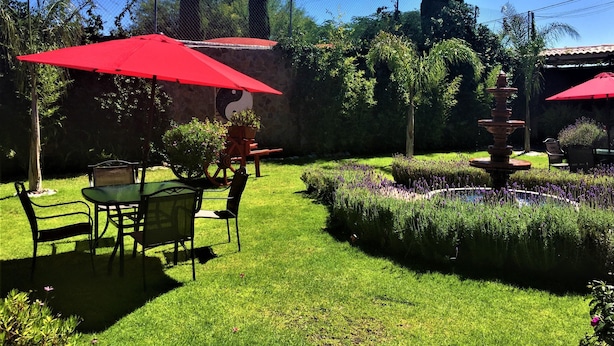 A well-maintained garden with a fountain, red umbrellas, and neatly trimmed hedges. - Hotel Boutique La Herencia (Tequisquiapan)