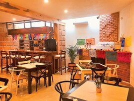 Un restaurante con mobiliario de madera, pared de ladrillo y zona de bar con botellas.