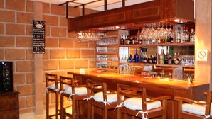 A bar area with wooden chairs, a bar counter, and shelves stocked with bottles and glasses. - Hotel Boutique La Herencia (Tequisquiapan)