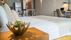 A neatly made bed with a decorative plant bowl on a wooden side table, a white pillow, and a white duvet. - Opal Apt. 402 Better in Person Than in the Pictures (Playa del Carmen)