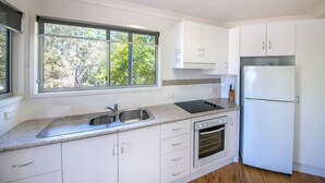 Una cocina moderna con armarios blancos, un lavamanos doble, un horno empotrado y un refrigerador.