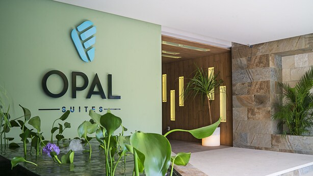 A hotel reception area with a sign reading "OPAL SUITES" and a water feature with plants. - Opal Apt. 202 Top Host Service, Ideal Location, Great Amenities (Playa del Carmen)