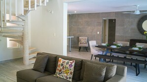 A modern living room with a staircase, a dining area with a table set for four, and a large mirror on the wall. - Casa Matuk 3 Refurnished Home Excelent for Family Retreat (Playa del Carmen)